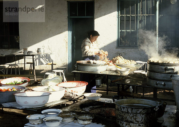 China  Provinz Xinjiang  Turpan  Frau beim Zubereiten von gedämpften Brötchen in der Außenküche