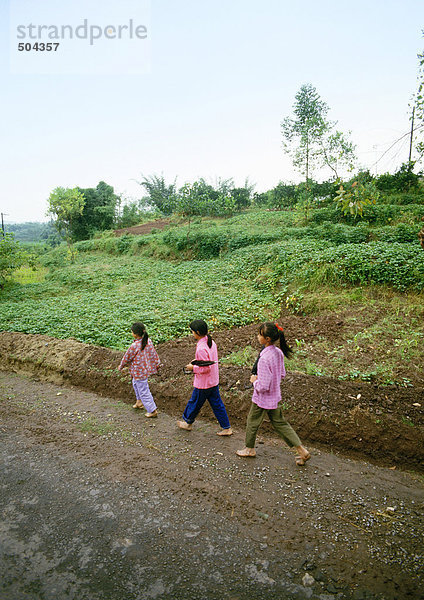 China  Autonome Region Guangxi  Kinder  die auf einem Feldweg im ländlichen Raum spazieren gehen.