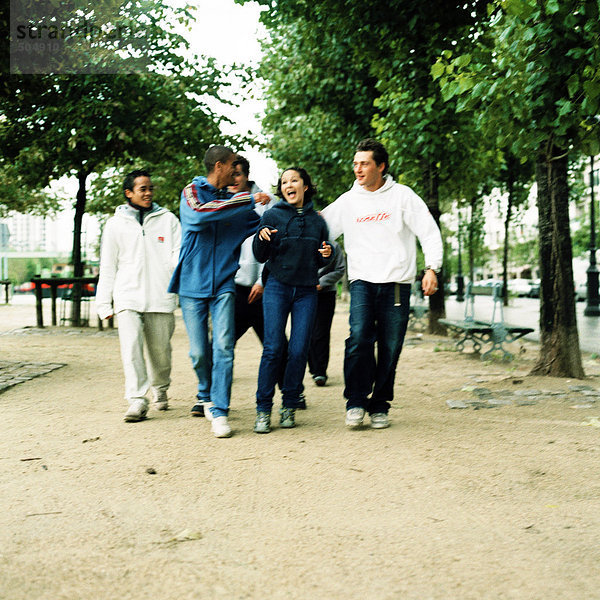 Gruppe von Teenagern  die Seite an Seite im Park spazieren gehen.