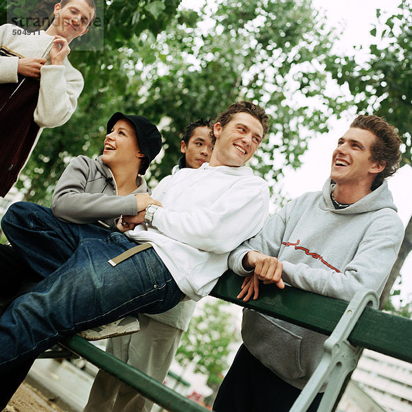 Junge Leute  die sich um die Bank im Park gruppiert haben.