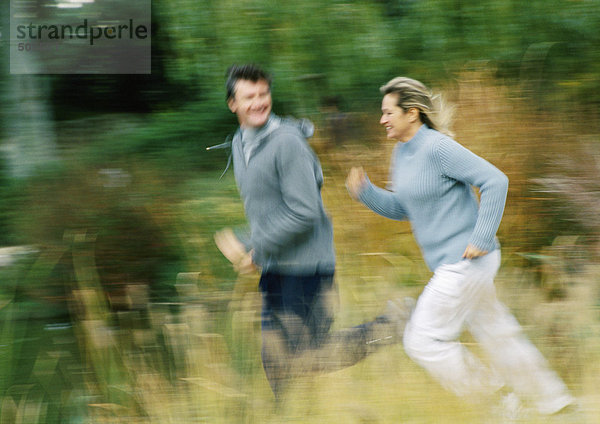 Mann und Frau joggen gemeinsam auf dem Feld  verschwommen
