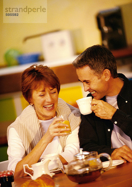 Mann und Frau beim Frühstücken am Tisch sitzend  lächelnd