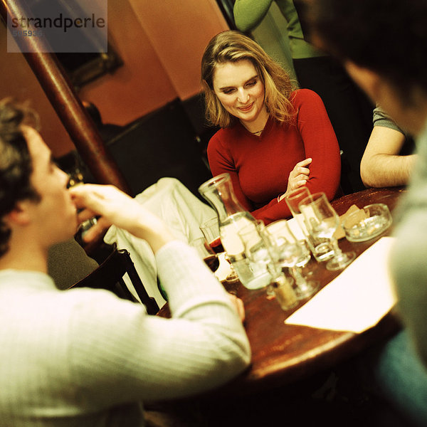 Gruppe junger Leute  die am Tisch sitzen und trinken.