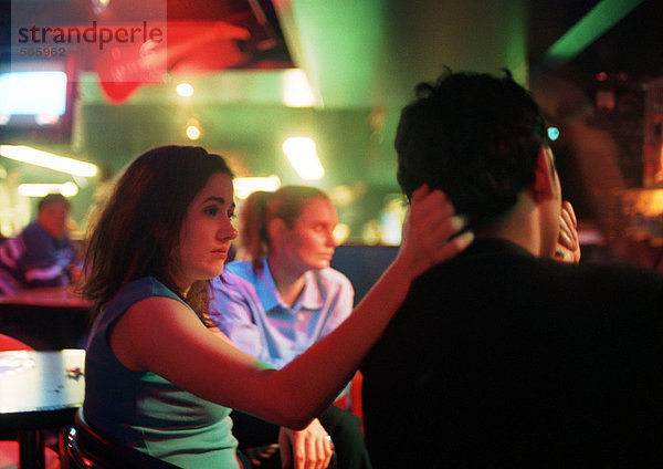 Junger Mann und junge Frau sitzend in der Bar