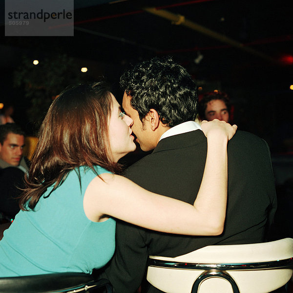 Junge Frau küsst jungen Mann auf Wange in der Bar  Rückansicht