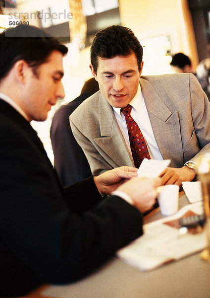 Geschäftsleute  die sich Papier bei Kaffee anschauen.