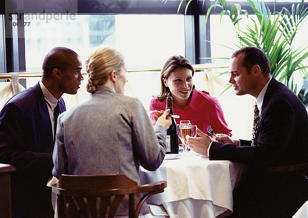 Gruppe von Geschäftsleuten  die am Tisch sitzen und essen.