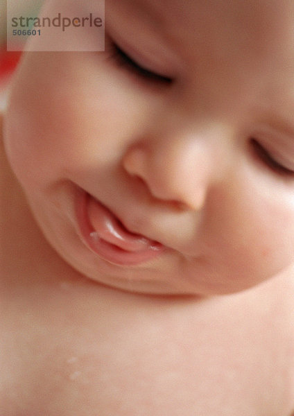 Baby mit geschlossenen Augen  herausstehende Zunge  Nahaufnahme.