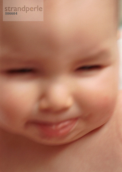 Baby streckt die Zunge raus  schielt  verschwommen  Nahaufnahme.