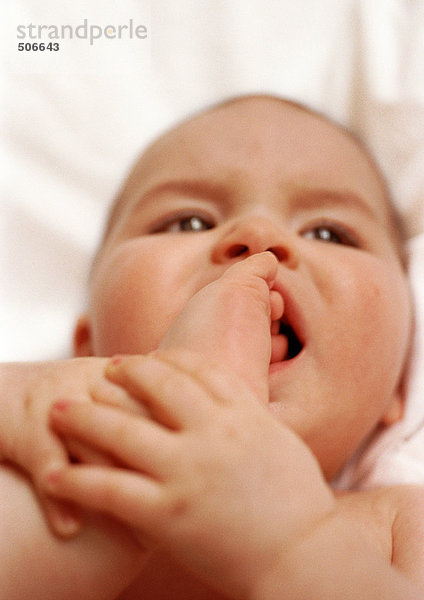 Baby liegt auf dem Rücken  tritt in den Mund  Nahaufnahme.