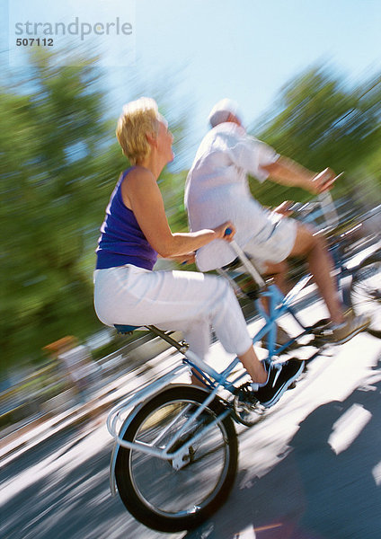 Erwachsener Mann und Frau  die zusammen auf einem Tandemrad fahren  verschwommen