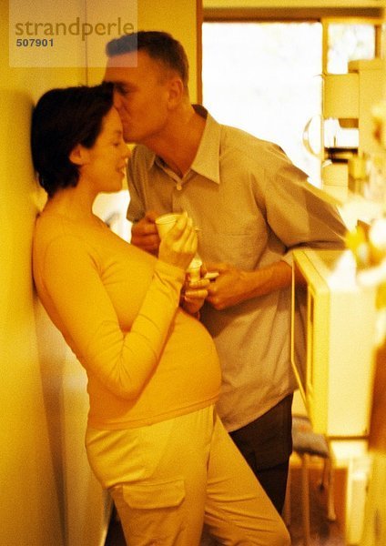 Mann  der die Stirn einer schwangeren Frau küsst  Gelbton