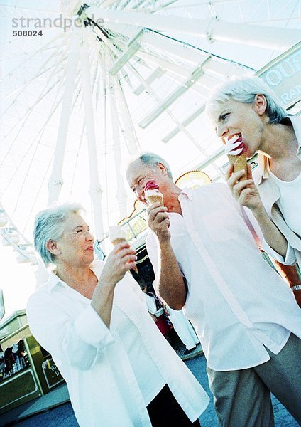 Freunde im Ruhestand essen Eis im Vergnügungspark