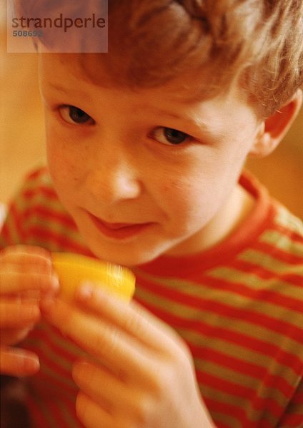 Kind hält Zitronenhälfte  Blick in die Kamera  Nahaufnahme  Portrait