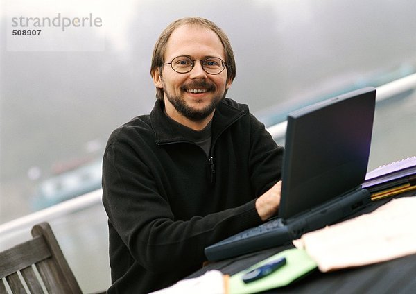 Mann mit Laptop im Freien  lächelnd  Portrait