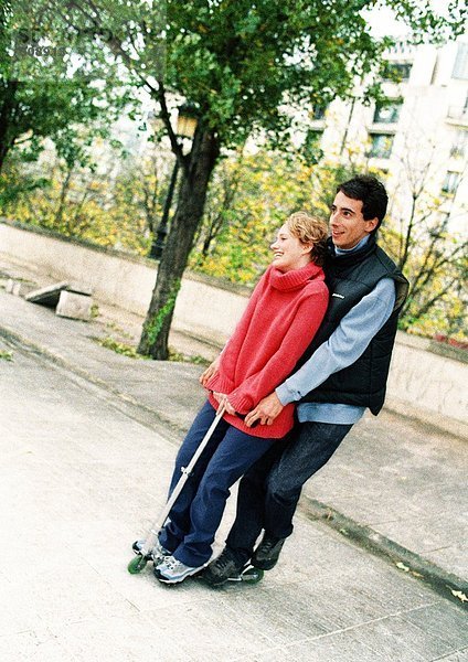Zwei junge Leute  die auf einem Roller stehen.
