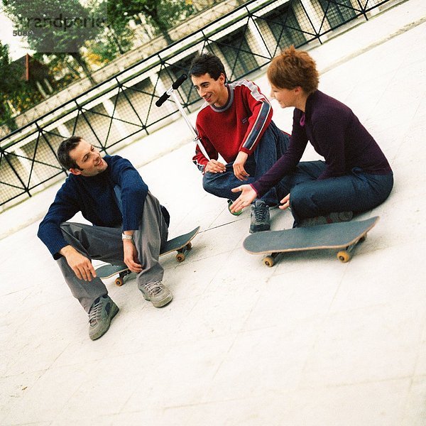 Jugendliche sitzen im Freien mit Skateboards