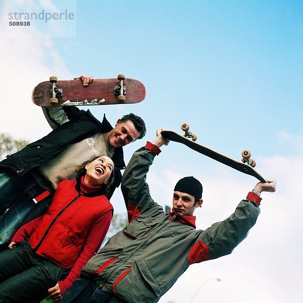 Junge Frau zwischen zwei jungen Männern mit Skateboard  Portrait