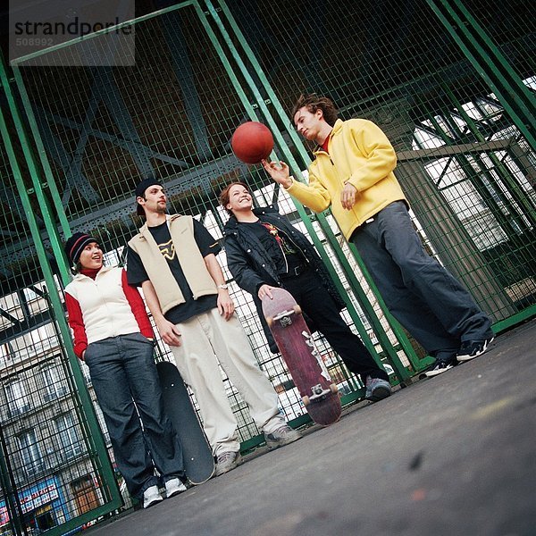 Junge Leute  die gegen den Zaun stehen  ein sich drehender Basketball