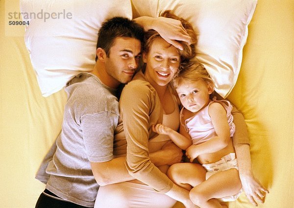 Paar und Kind auf dem Bett liegend  erhöhte Ansicht  Portrait