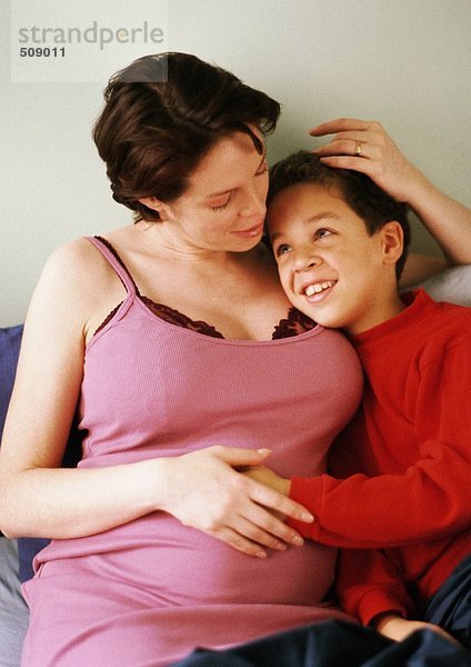 Schwangere Frau mit Arm um das Kind sitzend
