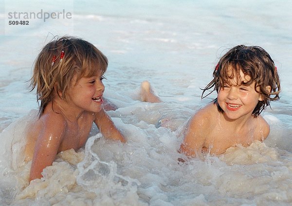 Zwei Mädchen spielen im Wasser und lächeln.
