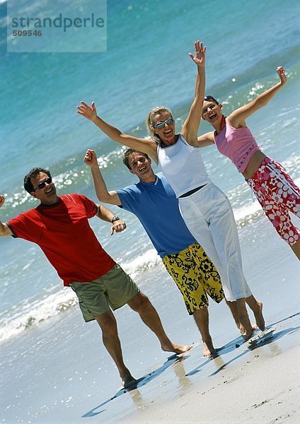 Familie mit zwei Teenagern am Strand  winkend