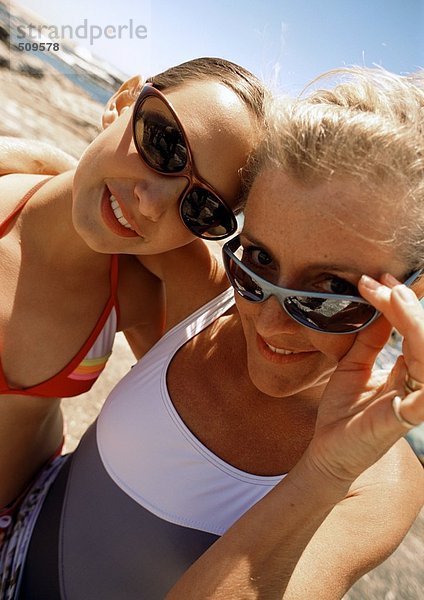 Nahaufnahme von Frau und Mädchen mit Sonnenbrille am Strand.