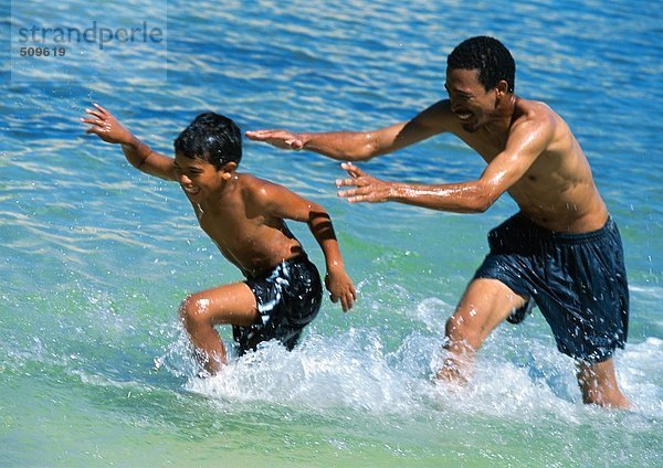 Mann und Sohn spielen im Meer