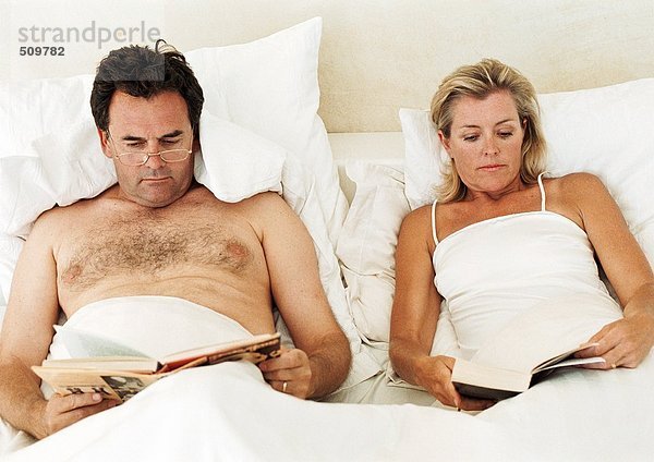 Paar im Bett liegend  lesend