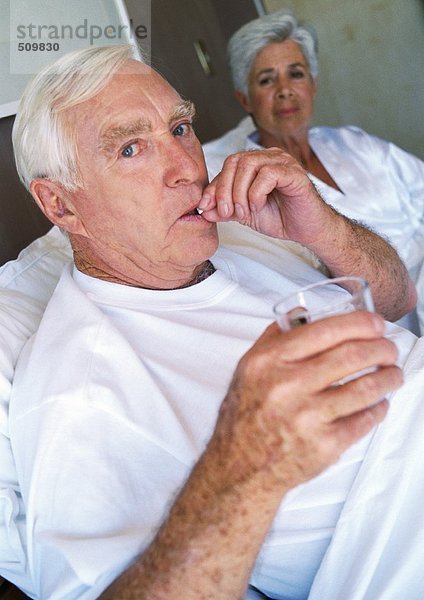 Seniorenpaar im Bett  Mann nimmt Pille