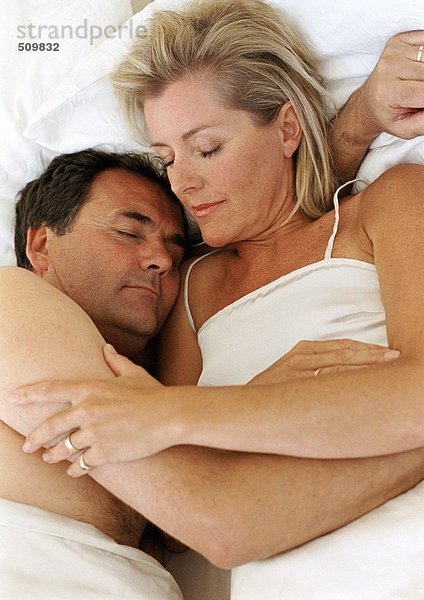 Ein Paar schläft im Bett  in den Armen des anderen.