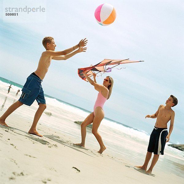 Zwei Jungen spielen mit Strandball  Frau hält Drachen
