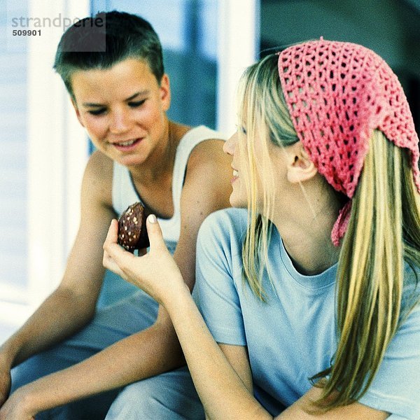 Junge Frau  die dem Teenager einen Brownie überreicht.