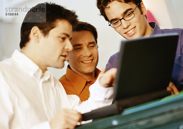 Drei Männer betrachten Laptop-Computer