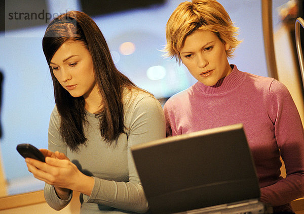 Zwei junge Frauen  eine mit Laptop  eine mit Telefon