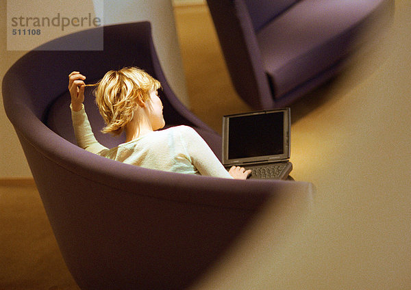 Frau auf dem Sofa sitzend mit Laptop  Rückansicht