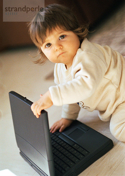 Baby spielt mit dem Laptop  schaut in die Kamera  Portrait.