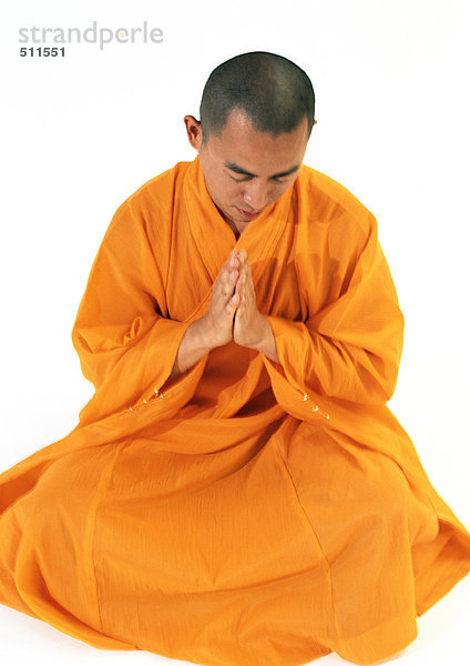 Buddhistischer Mönch sitzend  mit den Händen zusammen meditierend  hohe Blickwinkel