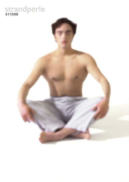 Oben-ohne-Mann auf dem Boden sitzend im indischen Stil  meditierend  verschwommen