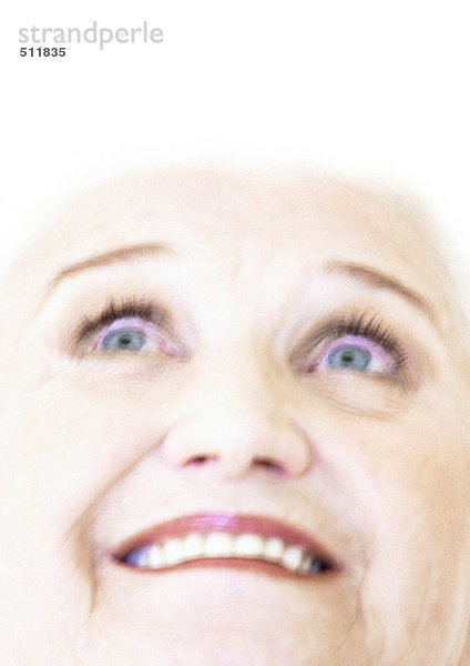 Ältere Frau lächelt  schaut nach oben.