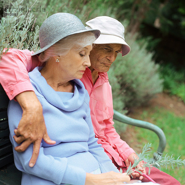 Seniorenpaar sitzend auf einer Bank im Freien