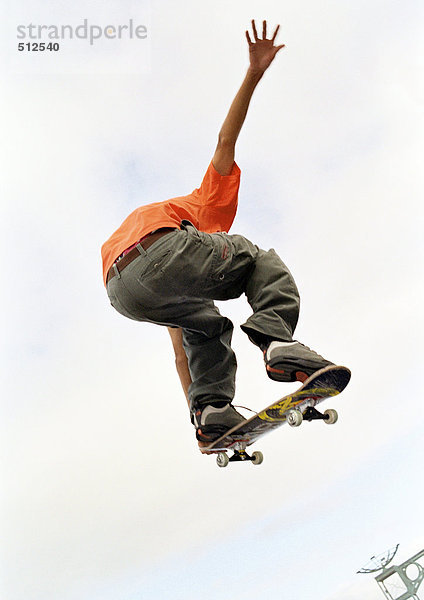 Junger Mann auf dem Skateboard  springen  in der Luft  niedriger Winkel  Rückansicht.