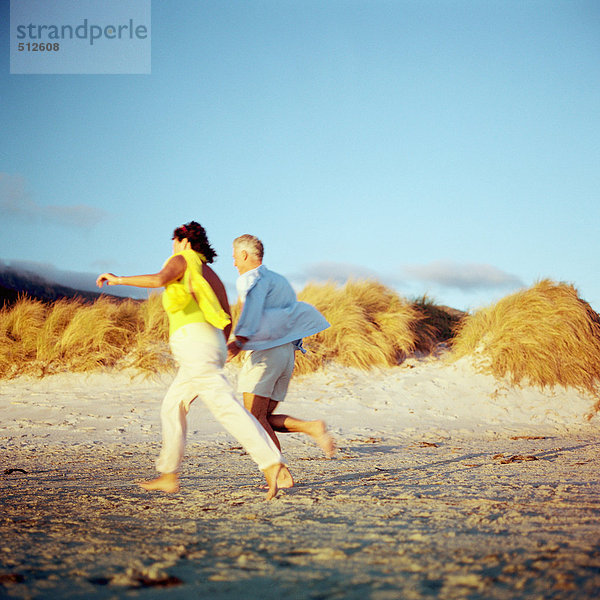 Älteres Paar läuft am Strand  Seitenansicht