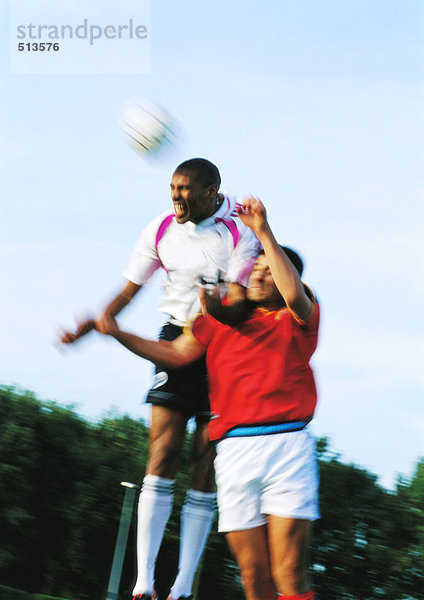 Zwei Spieler  die beim Fußballspiel um den Ball springen  verschwommene Bewegungen.