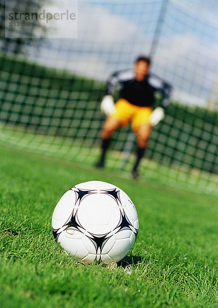Soccerball im Vordergrund  Torwart vor dem Tornetz  verschwommen im Hintergrund