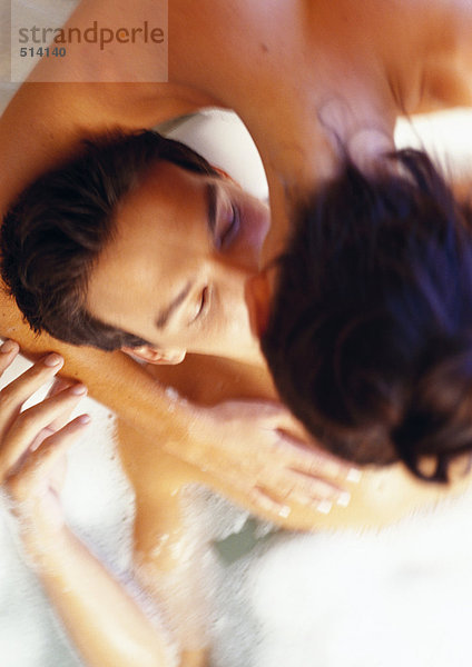 Frau beugt sich vor  küsst Mann im Bad
