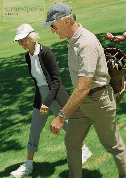 Reifer Mann und Frau auf Grün  Mann mit Golfschlägern