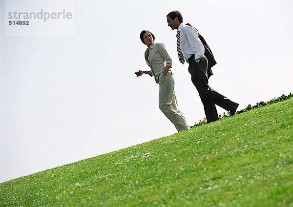 Geschäftsmann und Frau  die auf Gras laufen
