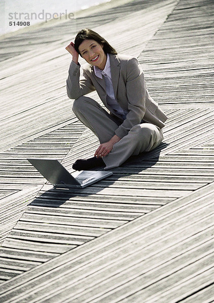 Geschäftsfrau am Boden sitzend mit Laptop  im Freien